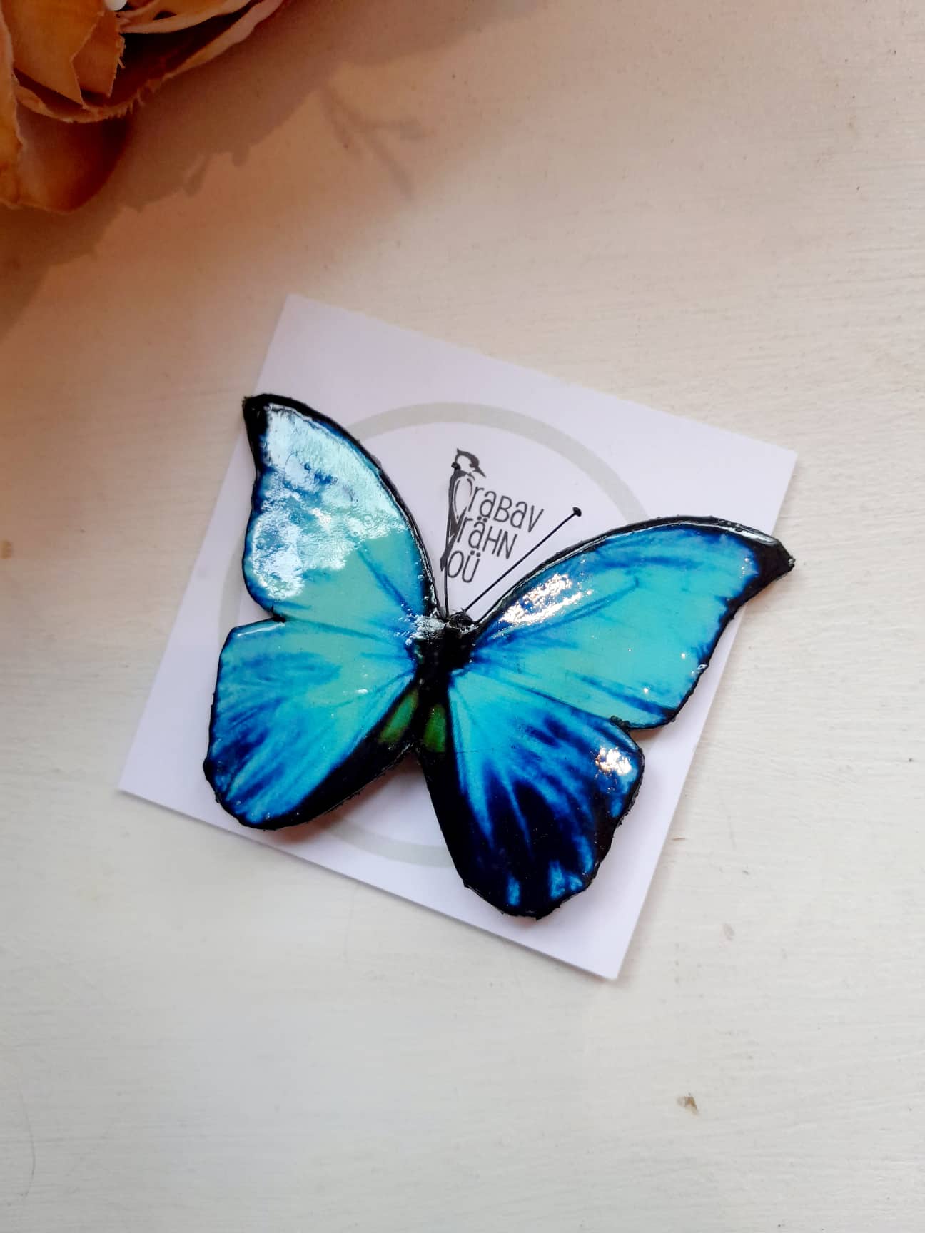 Musta äärisega, tumesinist värvi liblikakujuline pross